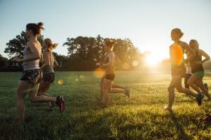 women running at sunrise in a field