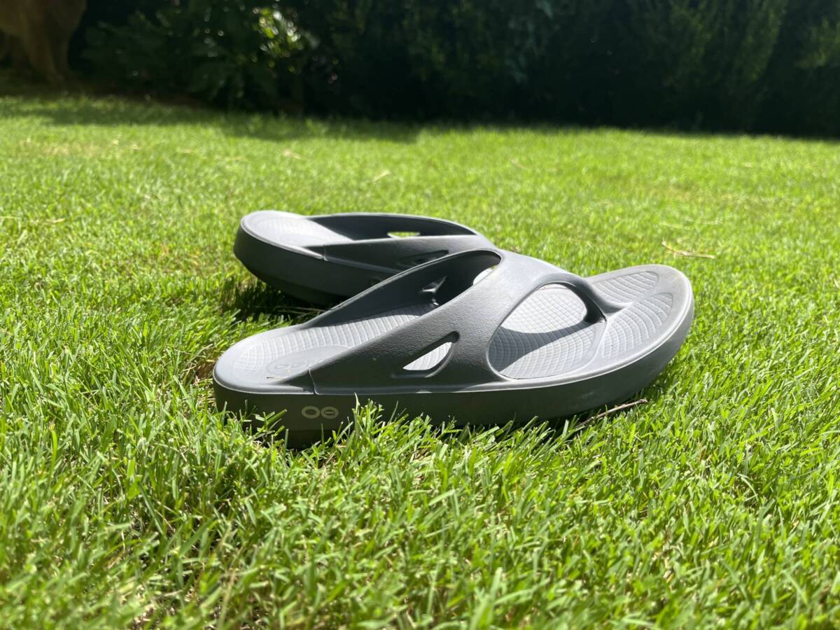 OOFOs recovery sandals on grass.