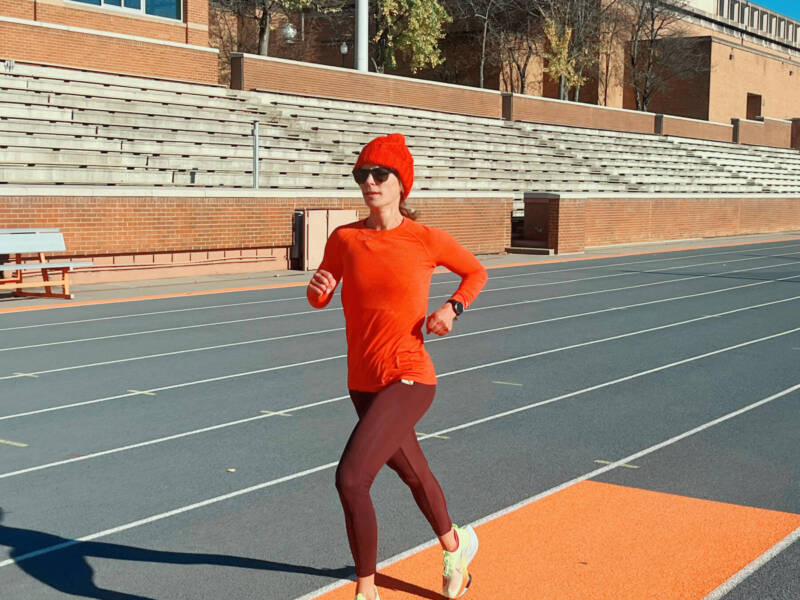 Whitney running on a track in winter running gear