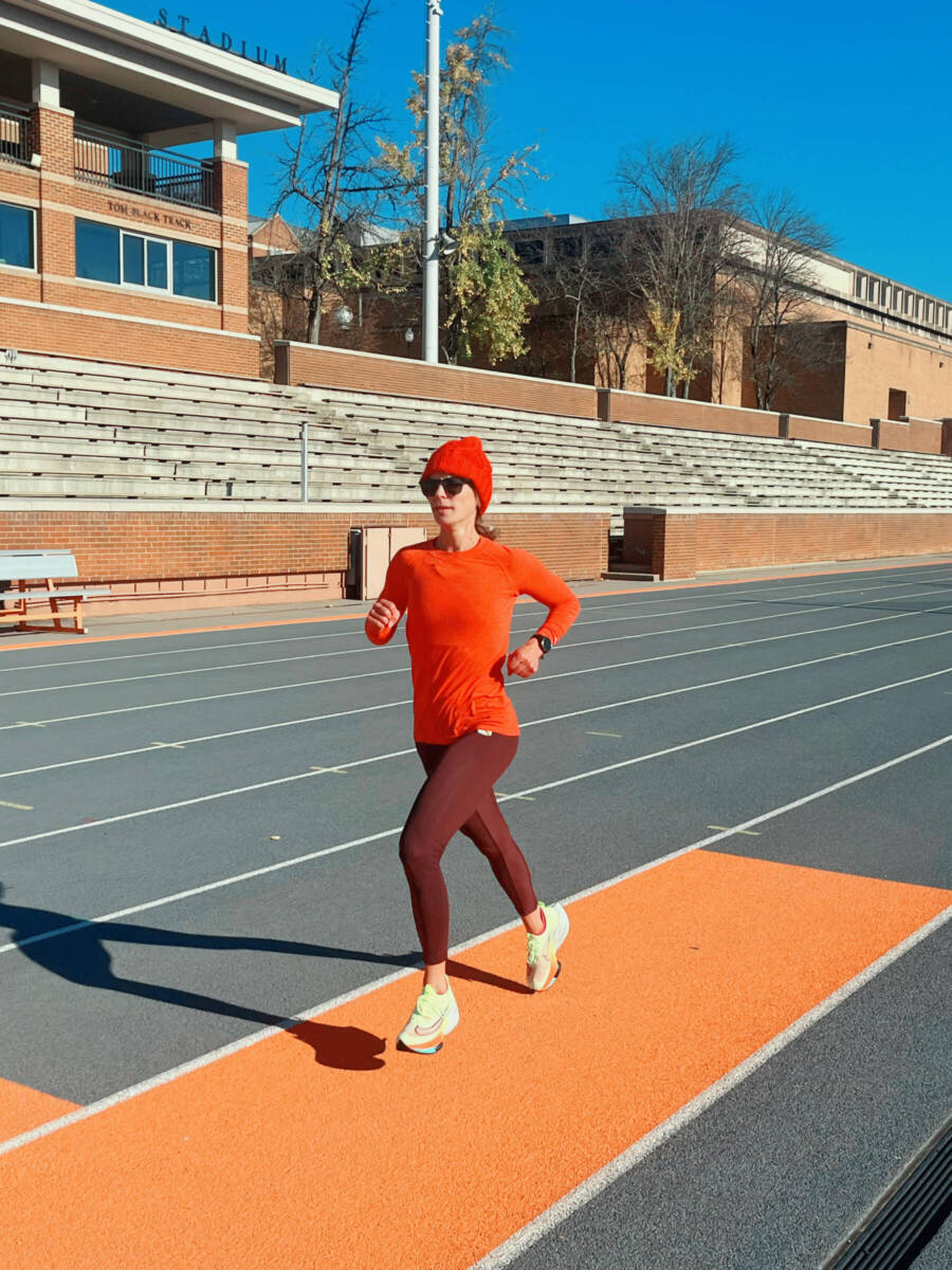 Whitney running on a track in winter running gear