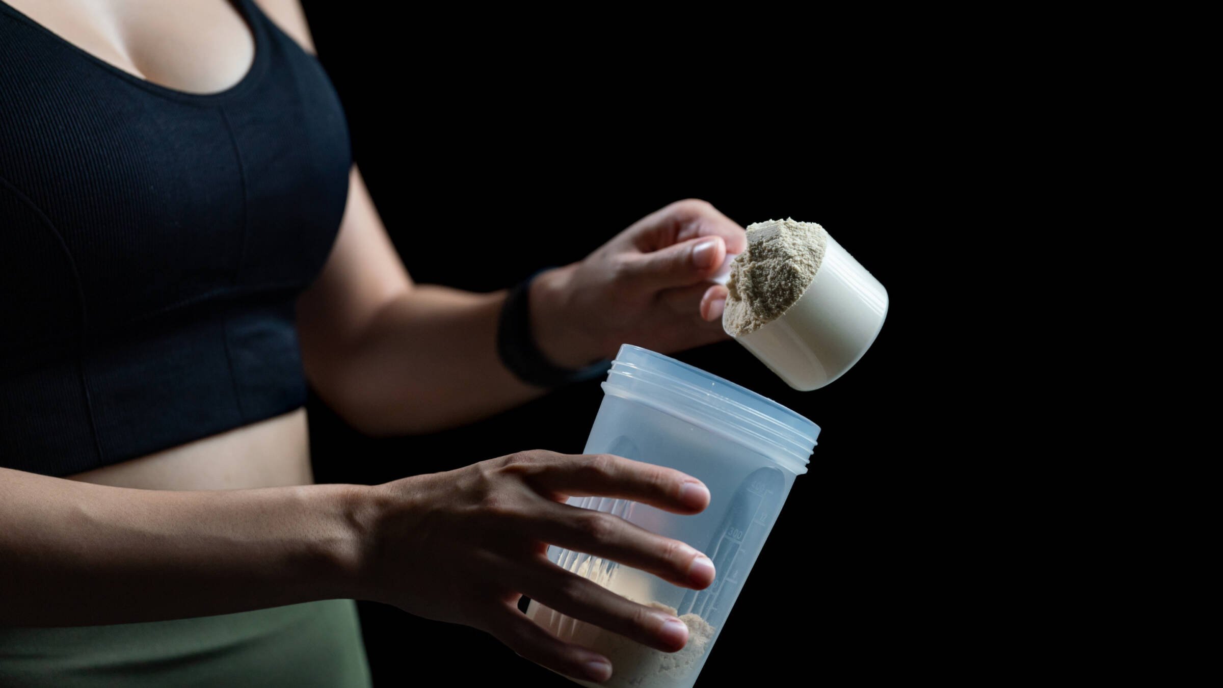 woman adding creatine to shake