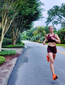 Whitney Heins running in red sports bra and red shorts.