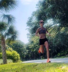 Whitney Heins running in black shorts and top. 