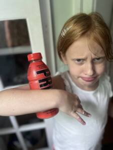 red headed girl with Prime drink