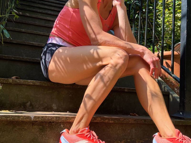 Whitney Heins sitting on steps wearing orange