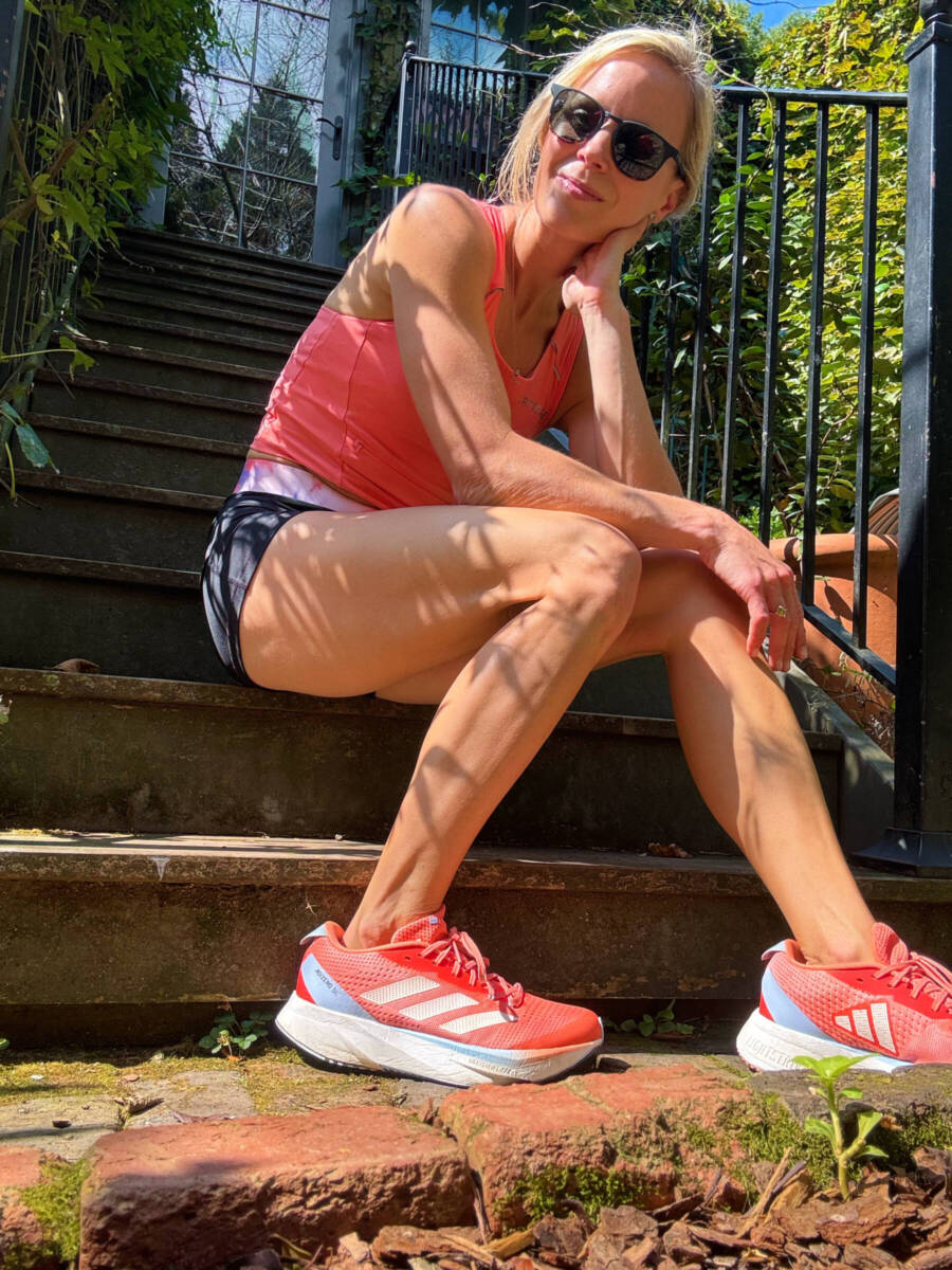 Whitney Heins sitting on steps wearing orange