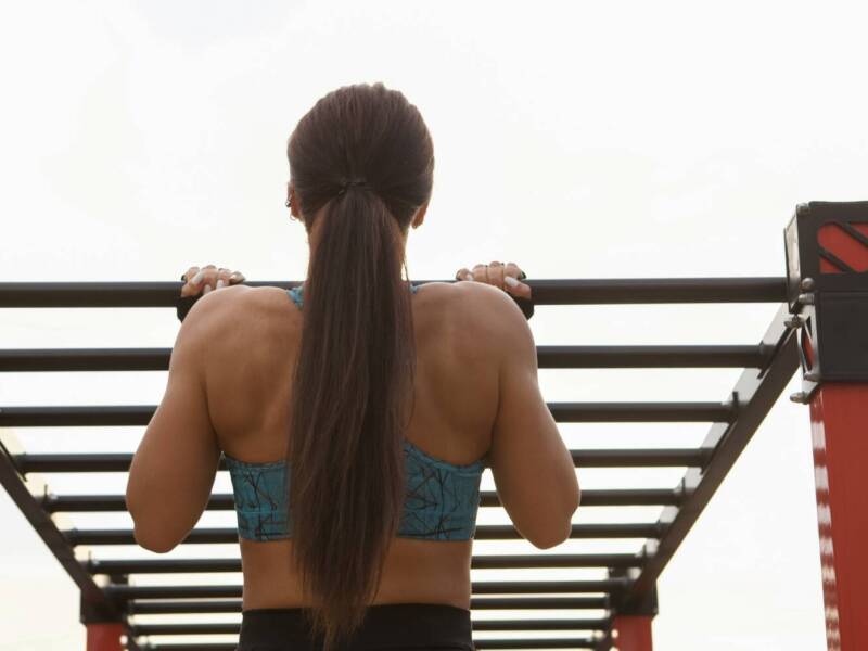 playground workout woman doing pull-ups on monkey bars