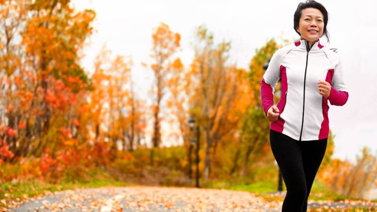 older woman running in fall forest