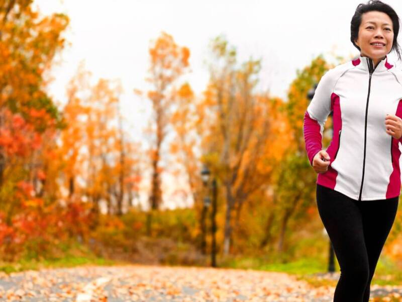 older woman running in fall forest