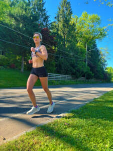 Whitney Heins running in a sports bra and smiling